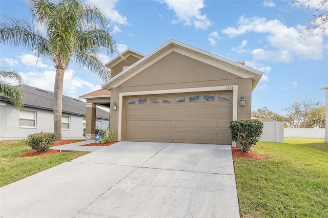 view of front of home featuring a garage, concrete driveway, fence, a front lawn, and stucco siding