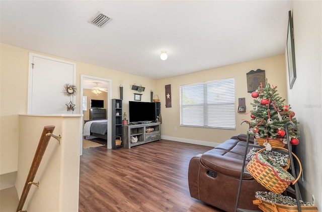 living room with dark wood finished floors, visible vents, and baseboards