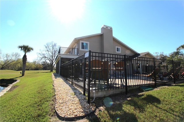 back of property with a wooden deck, a chimney, and a yard