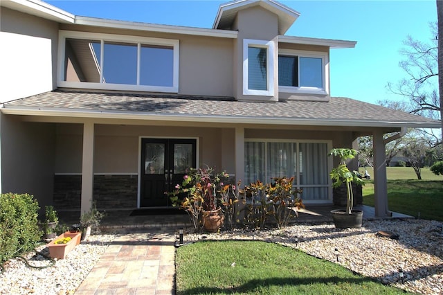 view of front of property featuring a porch, a shingled roof, stone siding, french doors, and stucco siding