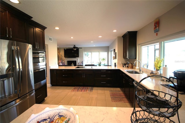 kitchen featuring appliances with stainless steel finishes, a fireplace, a sink, and recessed lighting