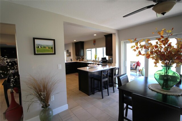 kitchen featuring light countertops, a ceiling fan, a sink, a peninsula, and a kitchen bar