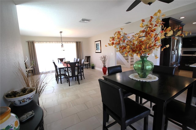 dining area featuring baseboards, stairway, visible vents, and a ceiling fan