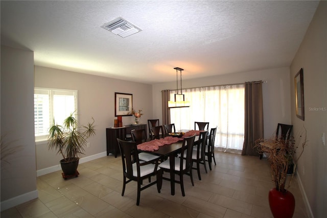 dining room with visible vents, a textured ceiling, and baseboards