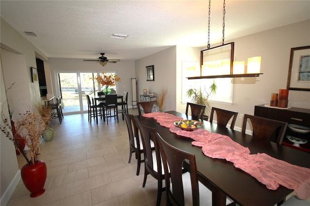 dining space with baseboards, ceiling fan, visible vents, and a textured ceiling