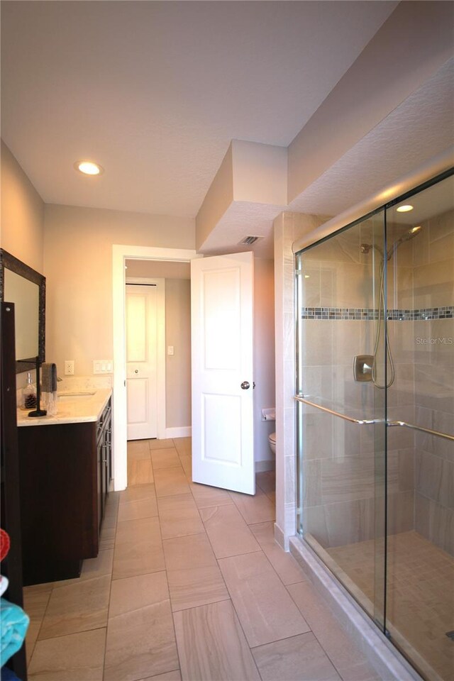 bathroom with toilet, a shower stall, baseboards, and vanity