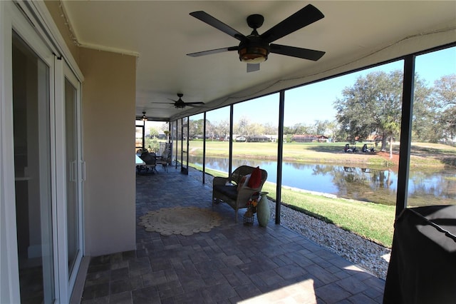 view of patio / terrace with a lanai, a water view, and a ceiling fan