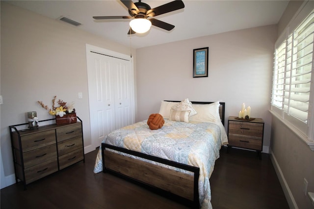 bedroom featuring baseboards, visible vents, a ceiling fan, dark wood-type flooring, and a closet