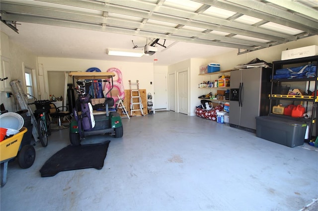 garage with stainless steel fridge and a garage door opener