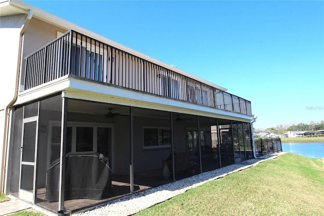 rear view of property featuring a yard, a water view, a sunroom, ceiling fan, and a balcony