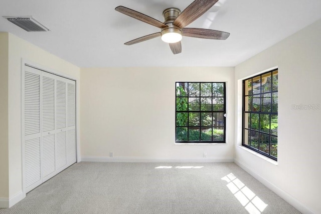 unfurnished bedroom with light carpet, a closet, and ceiling fan