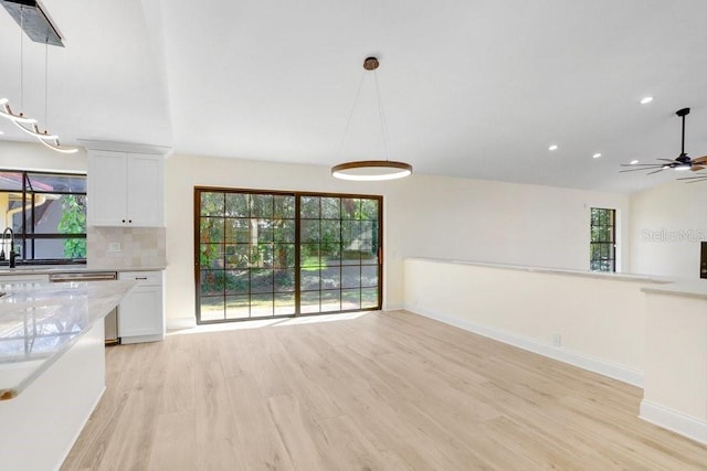 unfurnished dining area with ceiling fan, a wealth of natural light, lofted ceiling, and light hardwood / wood-style floors