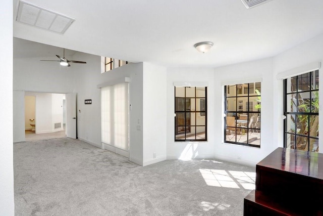 carpeted empty room with ceiling fan and a towering ceiling