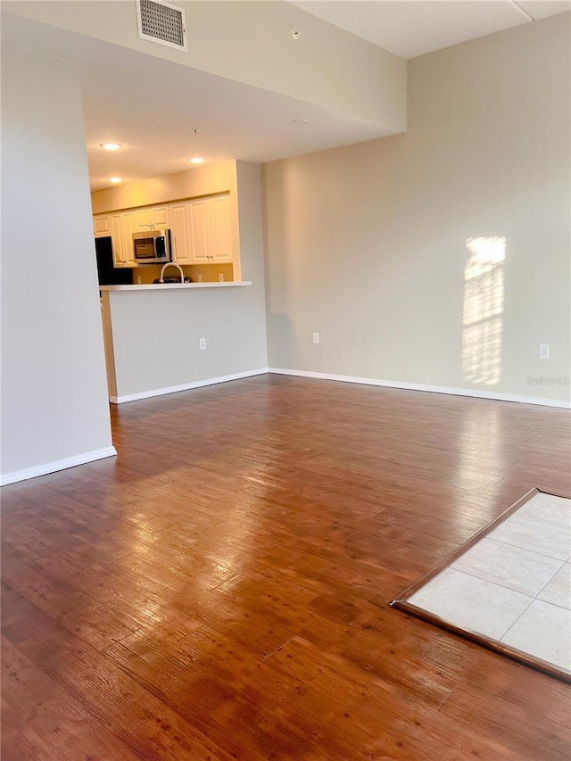 unfurnished living room with hardwood / wood-style floors and sink