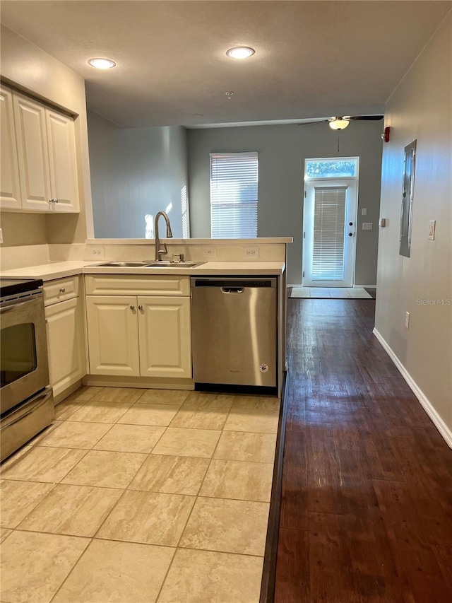 kitchen with appliances with stainless steel finishes, sink, kitchen peninsula, and white cabinets