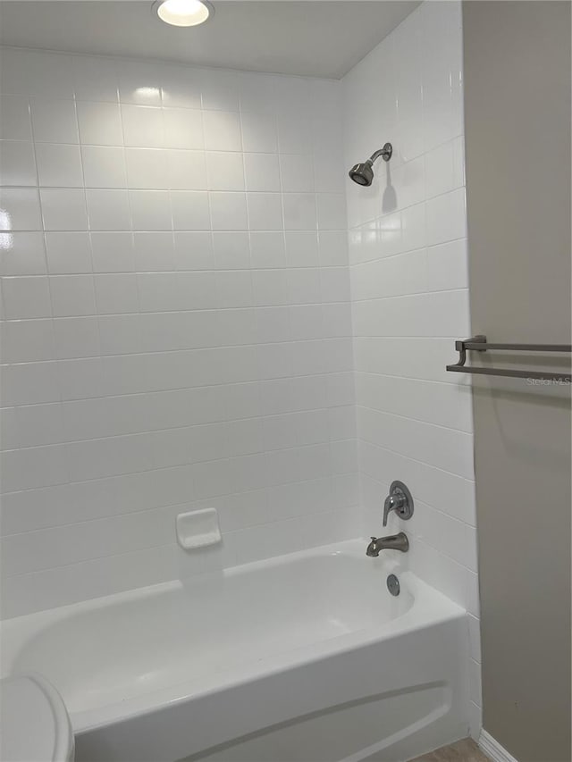 bathroom featuring tiled shower / bath combo and toilet