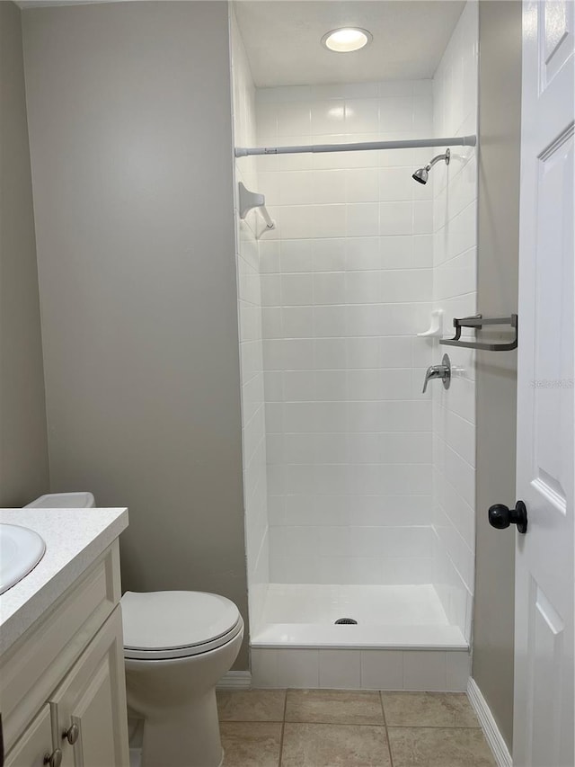 bathroom featuring tile patterned floors, toilet, vanity, and a tile shower