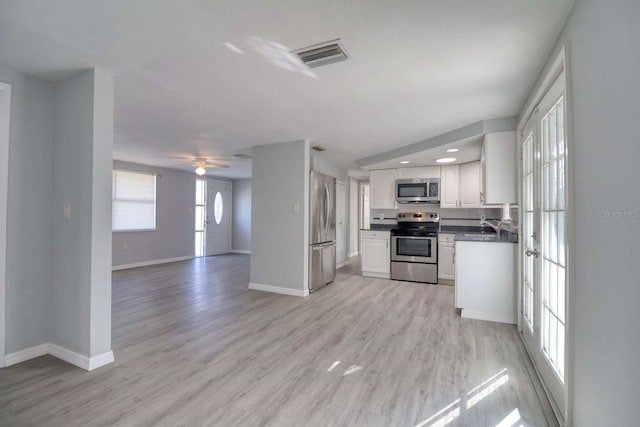 kitchen with white cabinetry, light wood-type flooring, stainless steel appliances, and ceiling fan