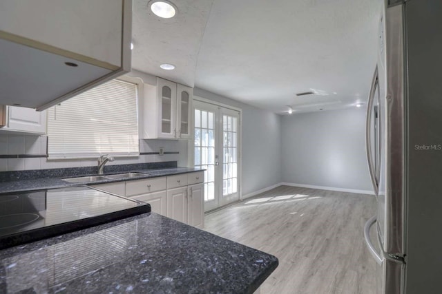 kitchen featuring sink, light wood-type flooring, white cabinetry, stainless steel refrigerator, and french doors