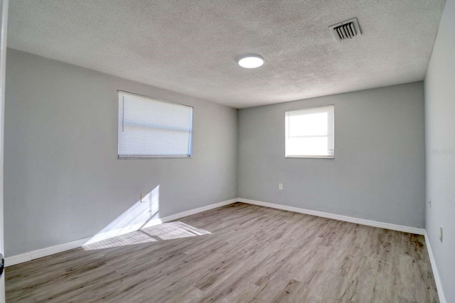 unfurnished room with light wood-type flooring and a textured ceiling