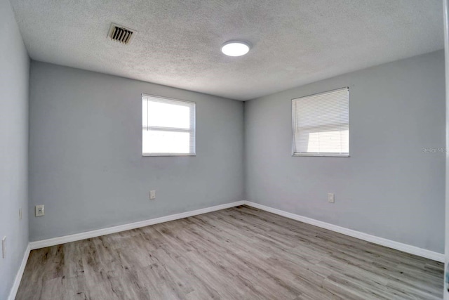 empty room featuring a textured ceiling and light hardwood / wood-style floors