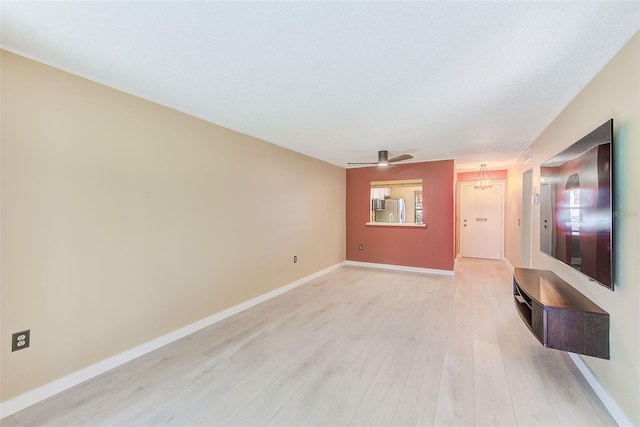 unfurnished living room with ceiling fan with notable chandelier and light hardwood / wood-style floors