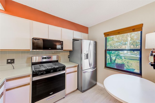 kitchen featuring decorative backsplash, stainless steel appliances, a textured ceiling, and white cabinets