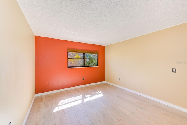 empty room with light hardwood / wood-style flooring and a textured ceiling