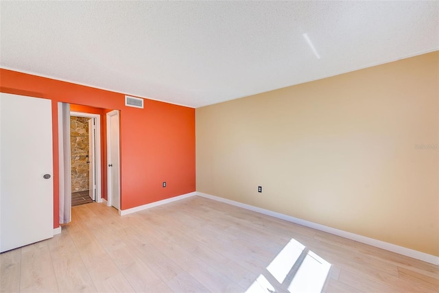 unfurnished room featuring a textured ceiling and light hardwood / wood-style floors