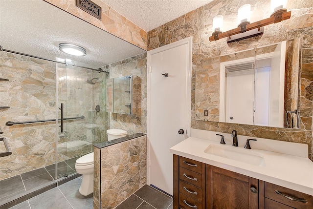 bathroom with a textured ceiling, toilet, vanity, and a shower with shower door