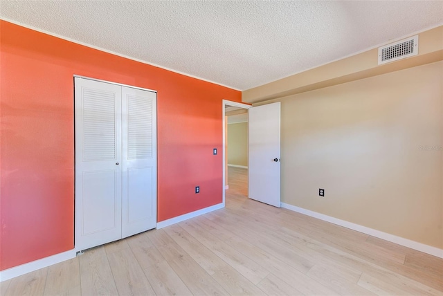 unfurnished bedroom featuring light wood-type flooring, a closet, and a textured ceiling