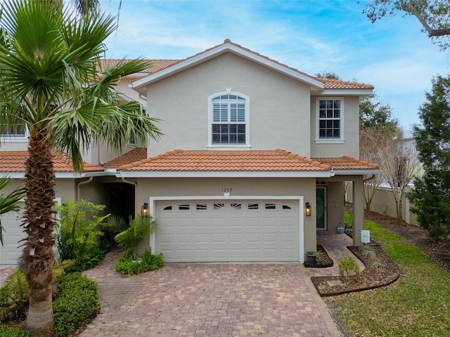 view of front of property featuring a garage, decorative driveway, a tiled roof, and stucco siding