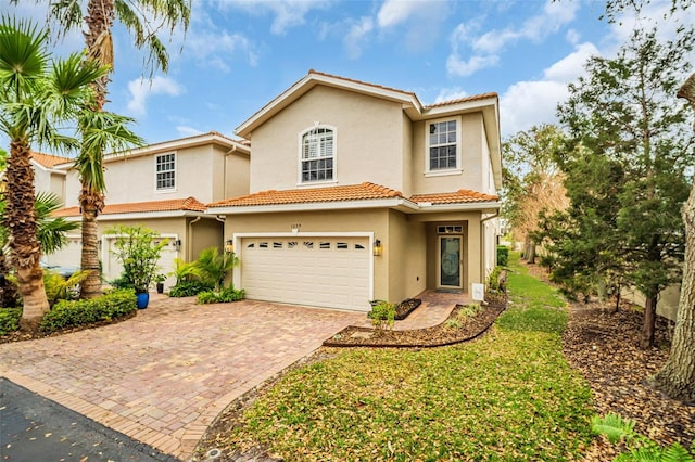 view of front of house featuring decorative driveway, an attached garage, a tile roof, and stucco siding