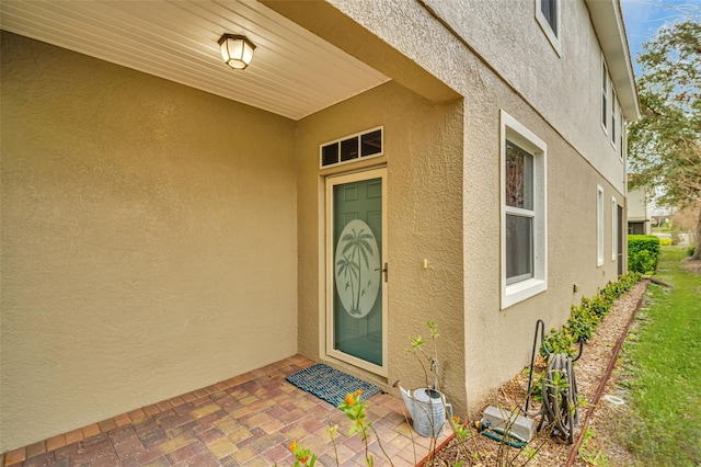 view of exterior entry featuring a patio and stucco siding