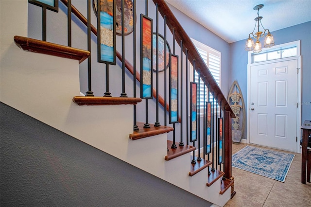 foyer entrance featuring light tile patterned floors, stairway, and a chandelier