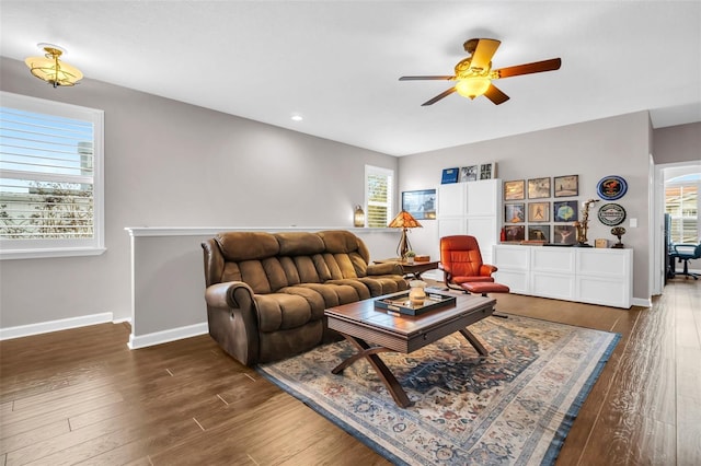 living room featuring dark wood-style flooring, a ceiling fan, and baseboards