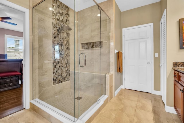 bathroom with a stall shower, baseboards, a ceiling fan, and vanity