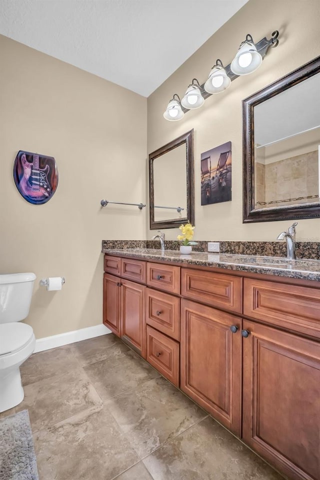 full bathroom featuring toilet, double vanity, baseboards, and a sink