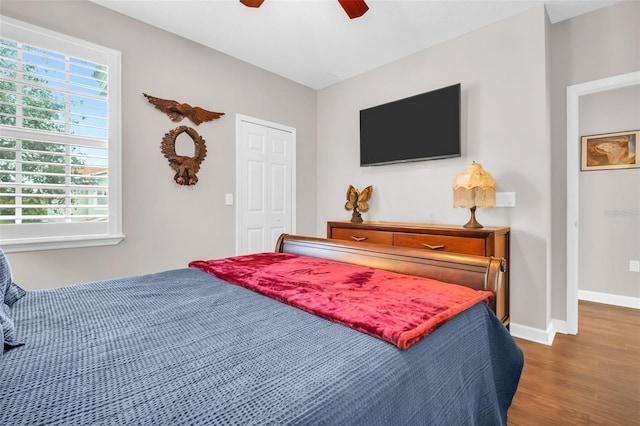 bedroom featuring a ceiling fan, a closet, baseboards, and wood finished floors