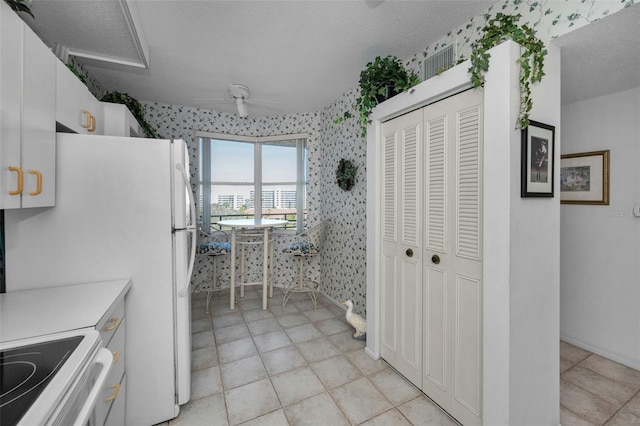 kitchen featuring ceiling fan, white cabinetry, white range with electric cooktop, and a textured ceiling