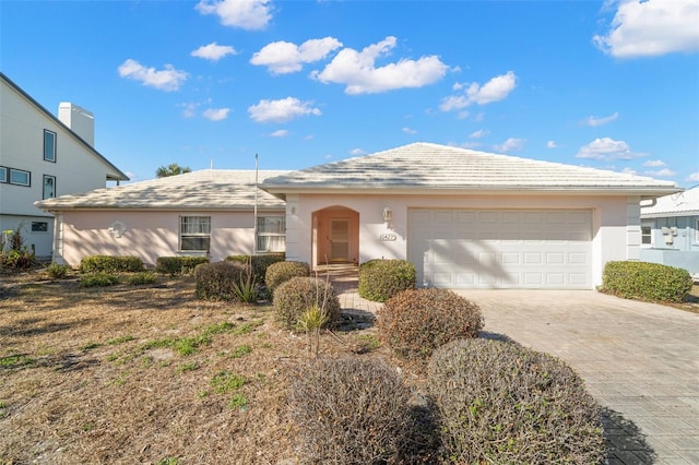 single story home featuring driveway, an attached garage, and stucco siding