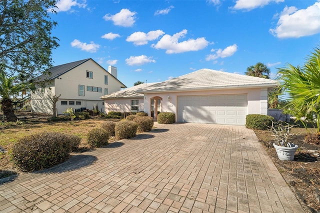 view of front of house featuring decorative driveway, an attached garage, and stucco siding