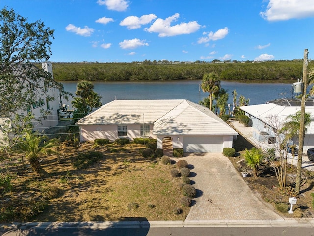 view of front of home with a water view, a garage, and decorative driveway