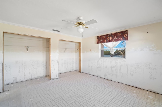 unfurnished bedroom with ornamental molding, a ceiling fan, visible vents, and two closets