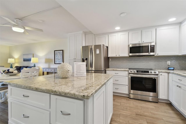3717 46th Ave S Unit 7, Saint Petersburg, FL 33711 - kitchen featuring appliances with stainless steel finishes, backsplash, light stone counters, light hardwood / wood-style floors, and white cabinets