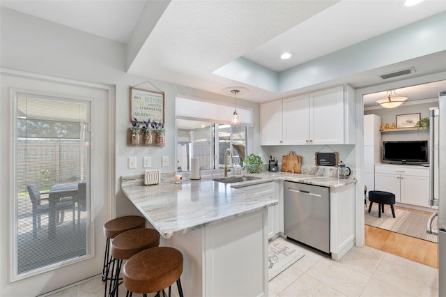 kitchen featuring a breakfast bar, visible vents, a sink, dishwasher, and a peninsula