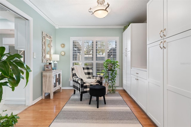 living area with light wood-style floors, baseboards, and ornamental molding