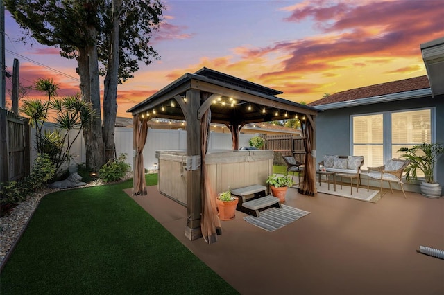 view of patio / terrace featuring a hot tub, an outdoor hangout area, a fenced backyard, and a gazebo