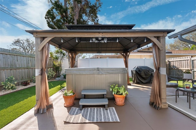 view of patio / terrace with a hot tub, a fenced backyard, area for grilling, and a gazebo