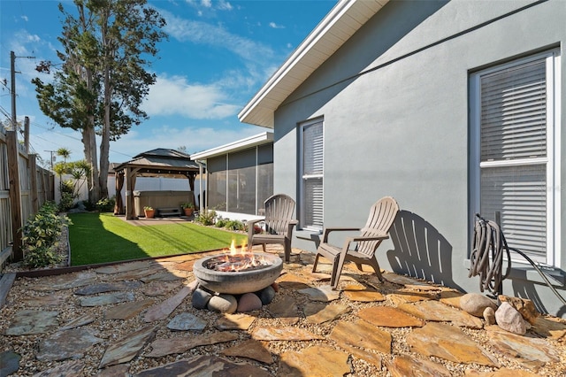 view of patio / terrace featuring a sunroom, a fenced backyard, a fire pit, and a gazebo